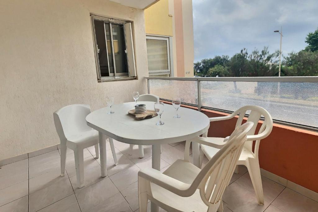 a white table and chairs on a balcony with a window at Confortable appartement pour 4 personnes proche de la plage in Valras-Plage