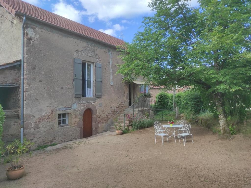 une table et des chaises devant un bâtiment dans l'établissement gite le vieux perrin, à Andelaroche