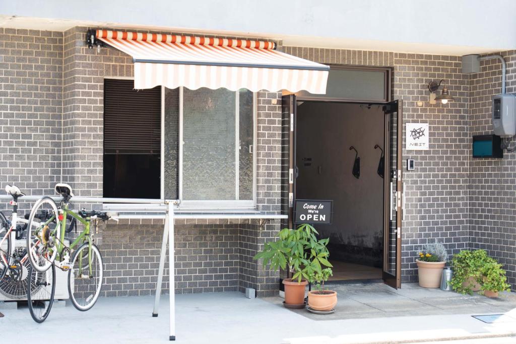 ein Fahrrad, das neben einem Gebäude mit Regenschirm geparkt ist in der Unterkunft 島宿Nest in Onomichi