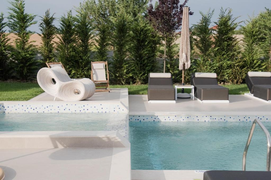 a pool with chaise lounge chairs and a swimming pool at Kallithea Village hotel in Kallithea Halkidikis