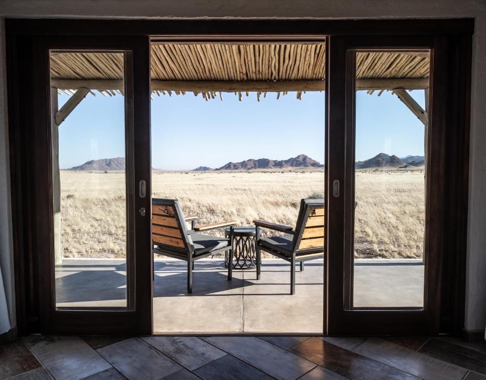 a porch with two chairs and a view of the desert at Desert Homestead Lodge in Sesriem