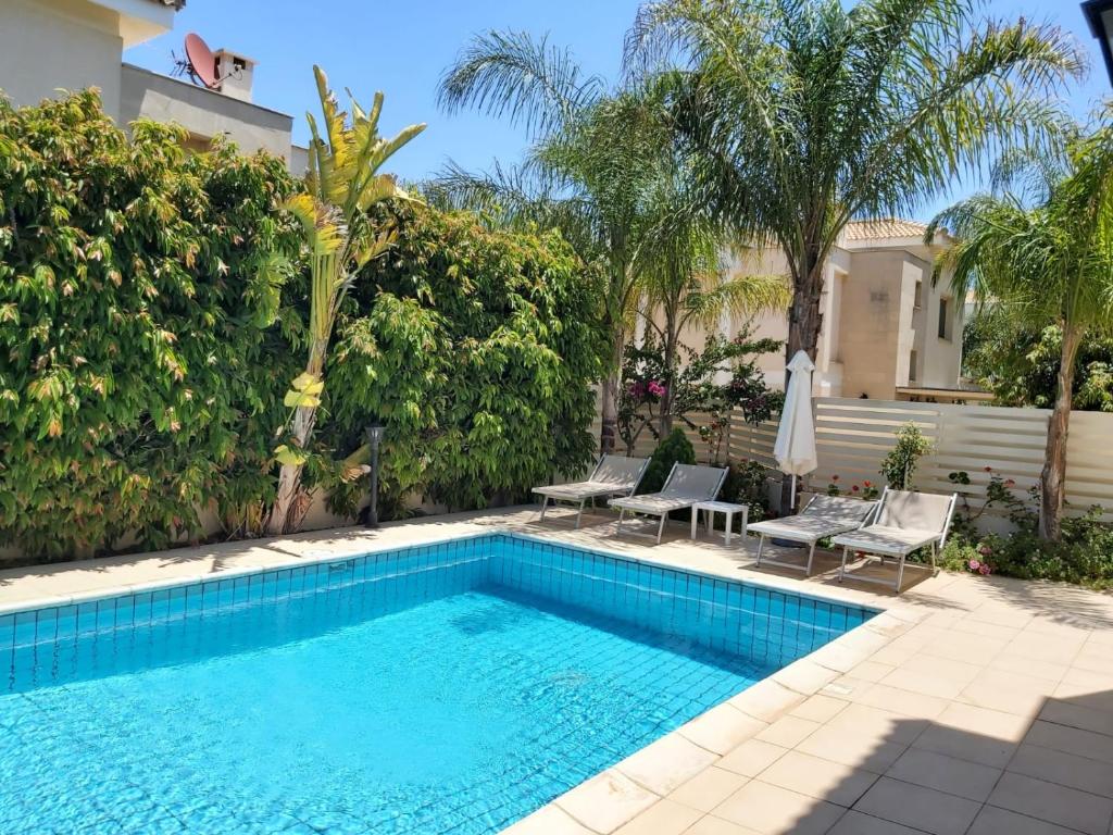 a swimming pool with chairs next to a house at Anthorina Villa 3 in Protaras