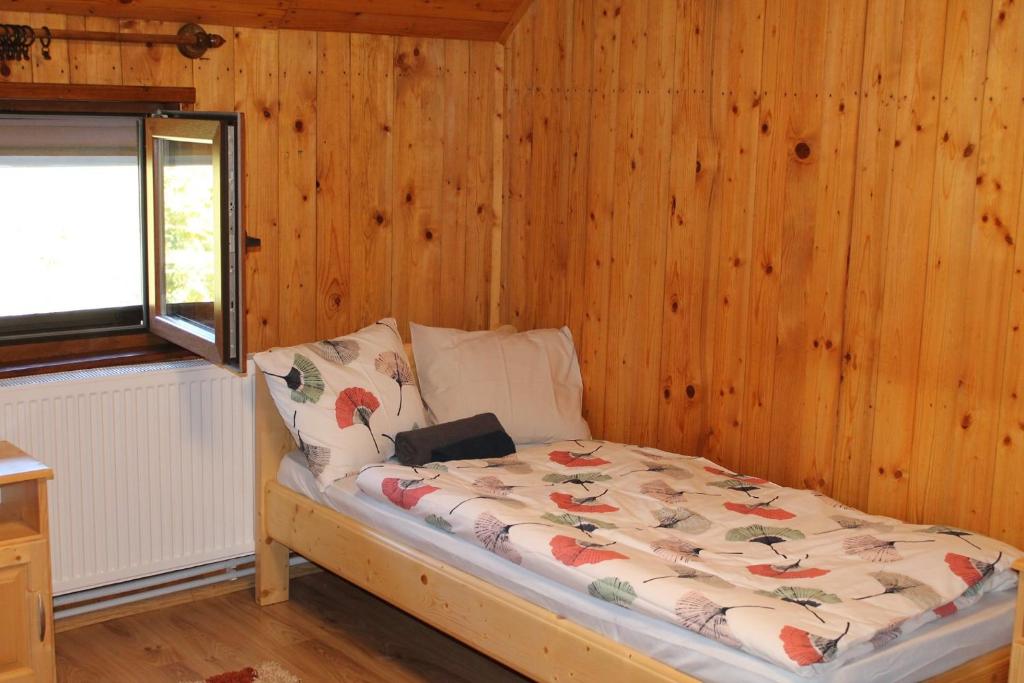 a bed in a room with a wooden wall at Patakvölgye Vendégház in Izvoare