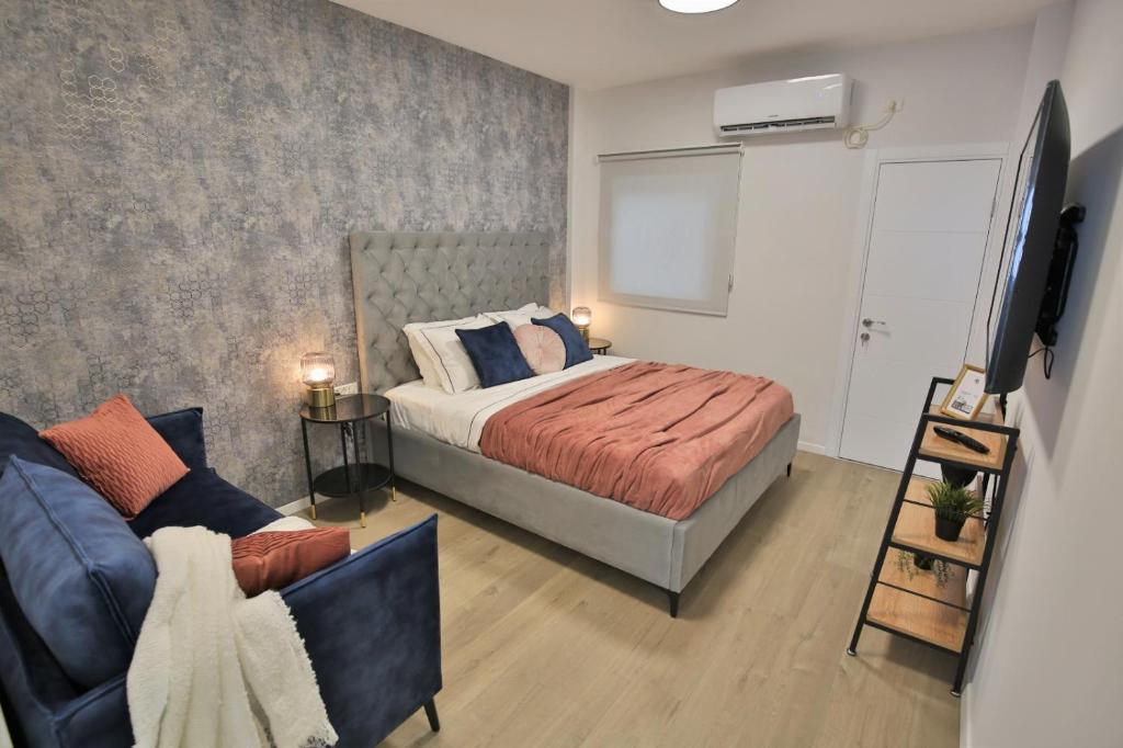 a bedroom with a bed and a couch and a tv at Cozy and stylish 1-bedroom apartment in Netanya