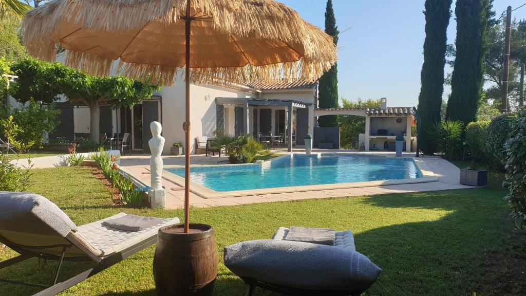 a house with a swimming pool and an umbrella at La Villa d'Olivène in Cuers