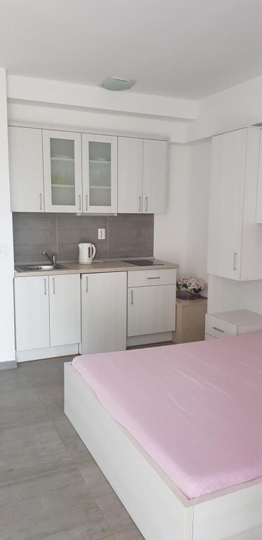 eine Küche mit weißen Schränken und einem rosa Bett in der Unterkunft Apartman Nikolić 1 in Makarska