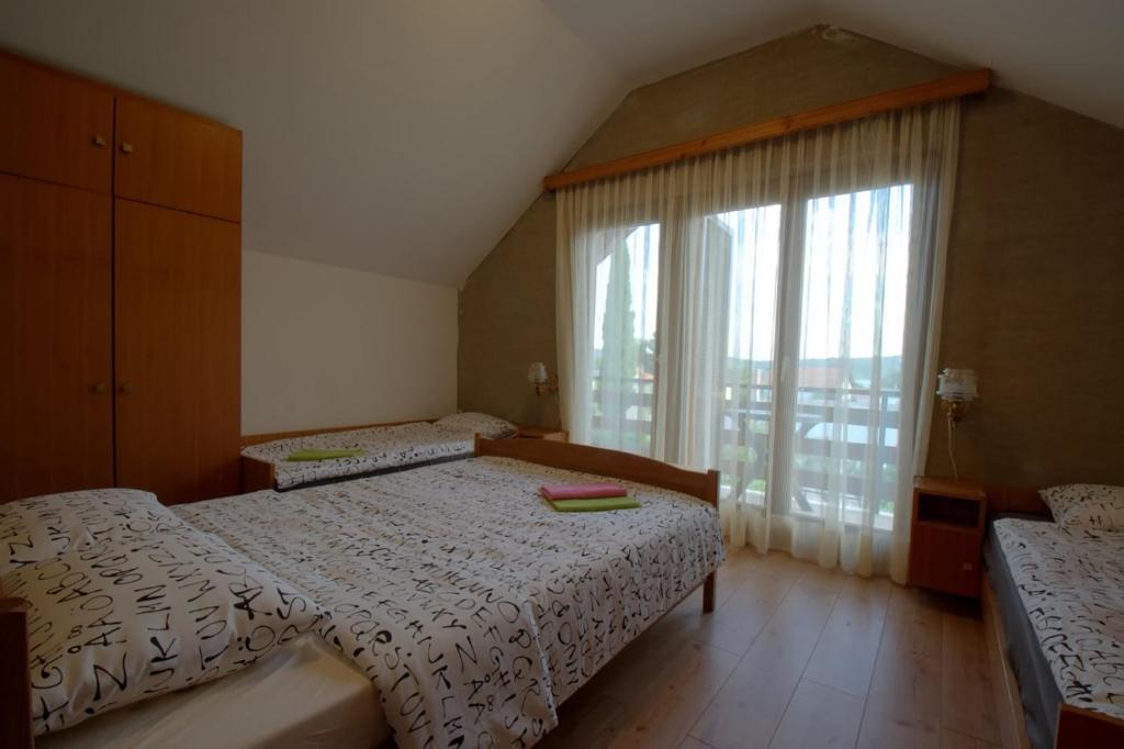 a bedroom with two beds and a large window at kuća za odmor Anić in Pirovac