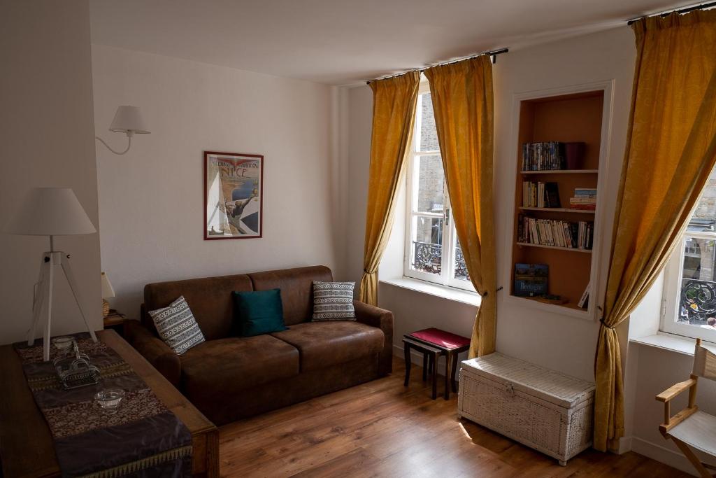 sala de estar con sofá y 2 ventanas en Appartement place Des Cordeliers, en Dinan