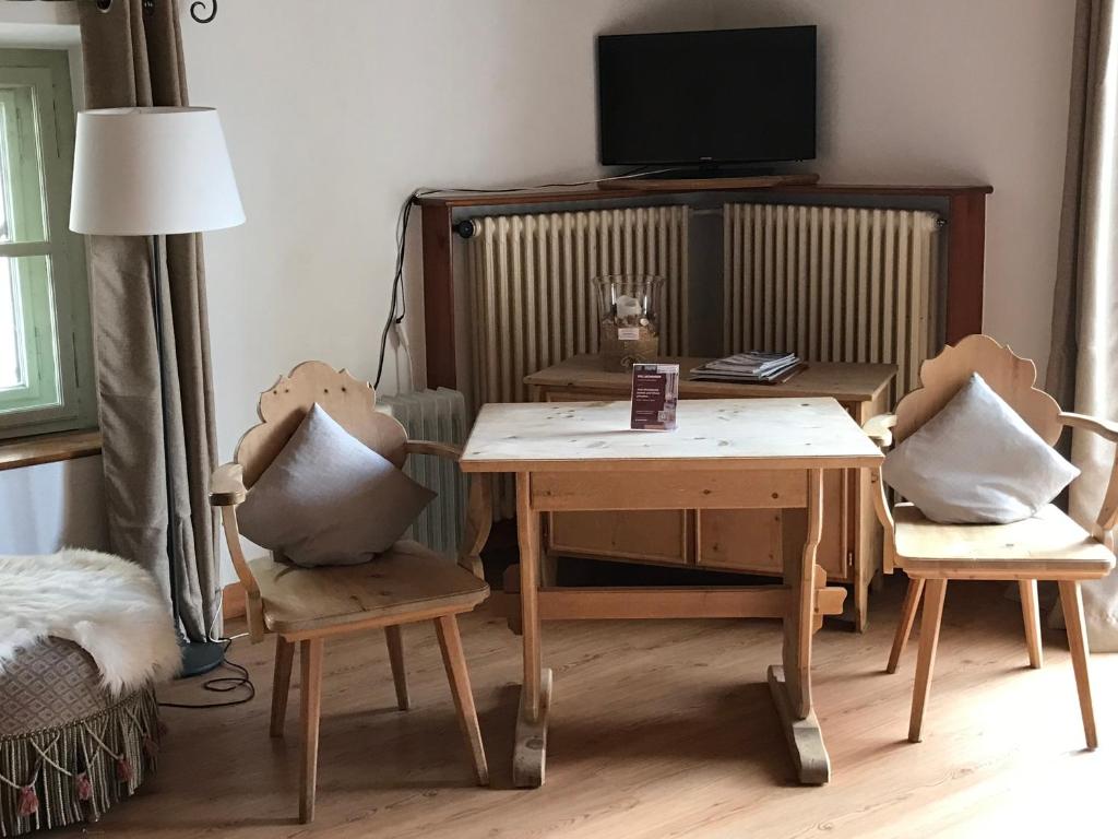 a living room with a table and chairs and a tv at Hotel Klarer in Zuoz