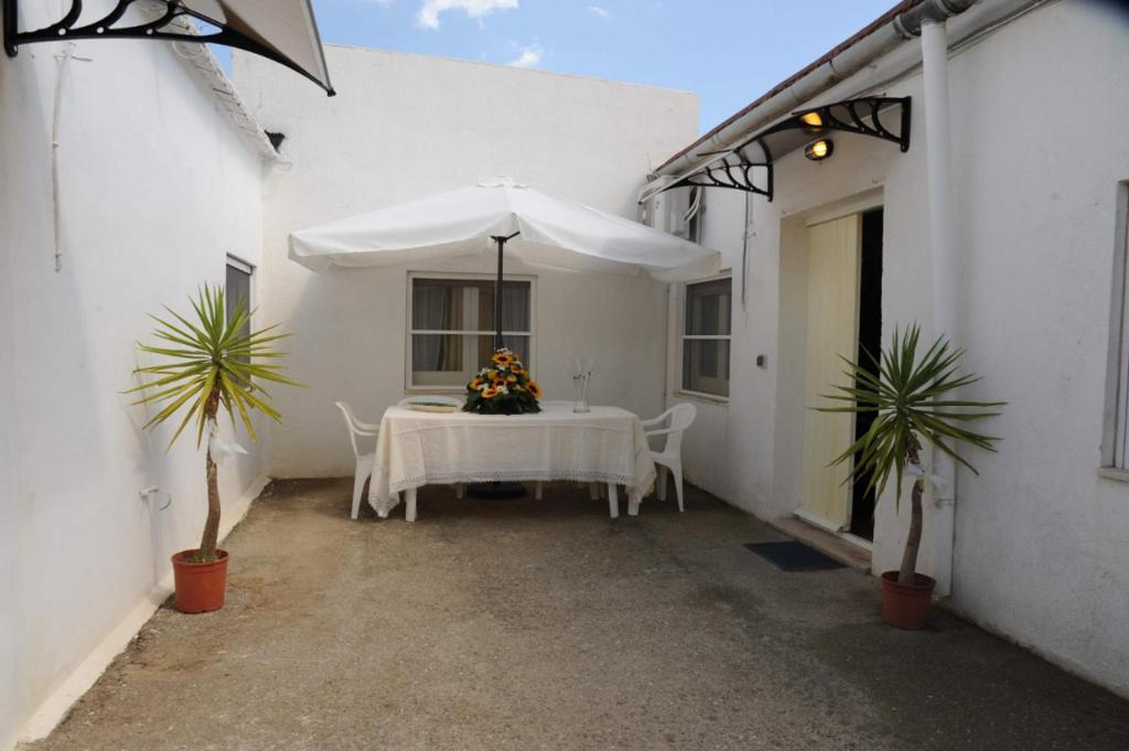 un patio blanco con mesa y sombrilla en Casa Marinella al confine fra Basilicata e Puglia, en Bernalda