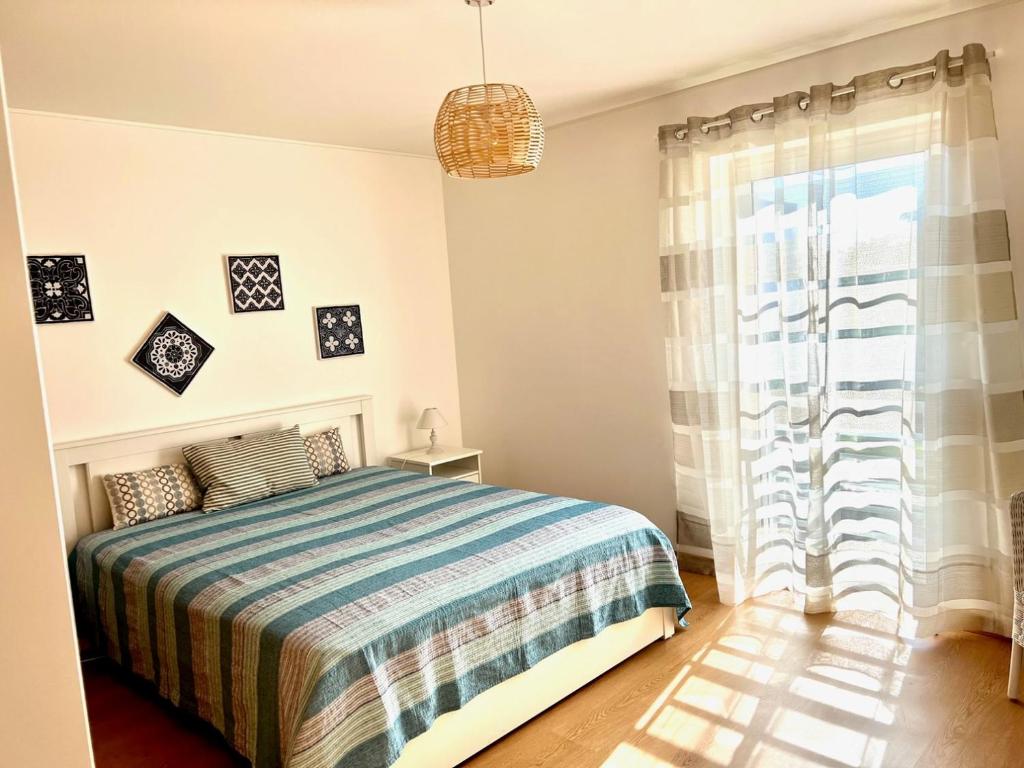 um quarto com uma cama e uma grande janela em Cabanas Wonder - 150mts from the beach em Cabanas de Tavira