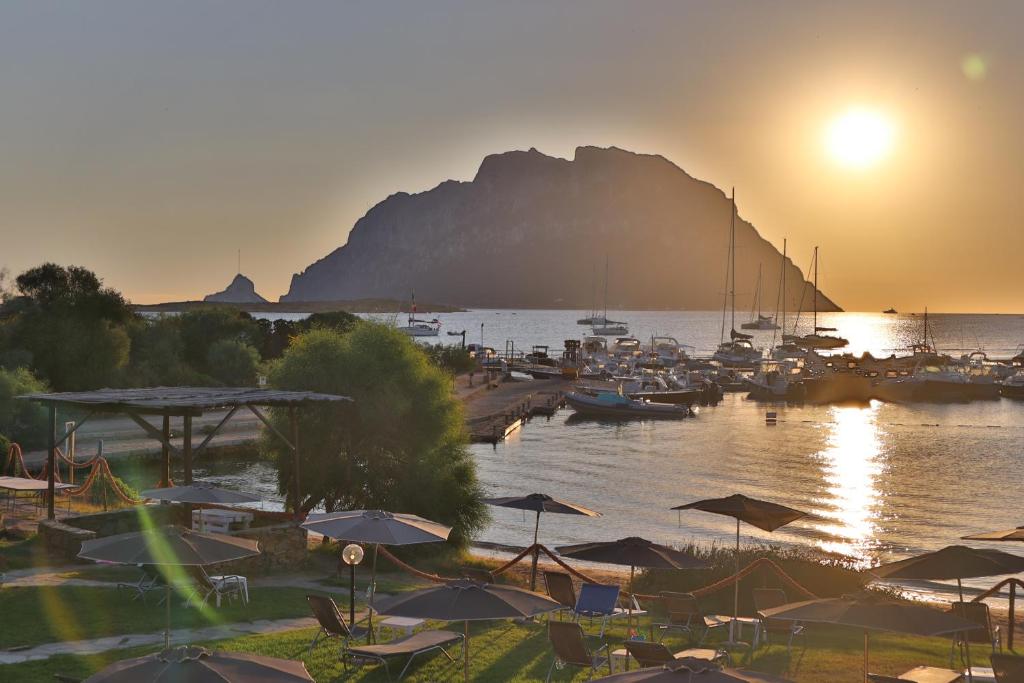 a group of boats in a harbor with the sun setting at IHR Hotel San Paolo in Porto San Paolo