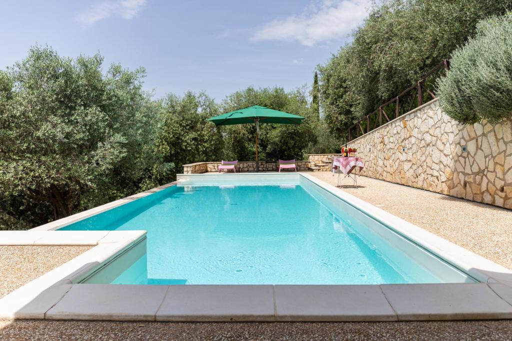 una piscina con una mesa y una sombrilla verde en La Tana delle Stelle B&B di Charme e Relax, en Fara in Sabina