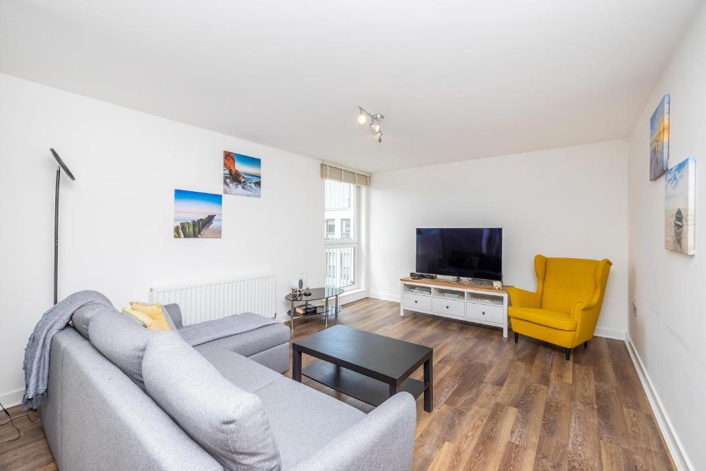 a living room with a gray couch and a yellow chair at ALTIDO Modern 2 bed flat near Inverleith Park, with terrace and free parking in Edinburgh