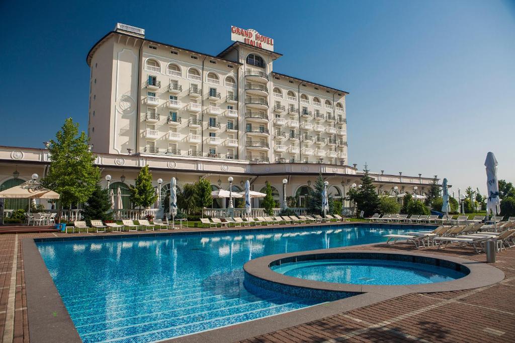 un hotel con piscina di fronte a un edificio di Grand Hotel Italia a Cluj-Napoca