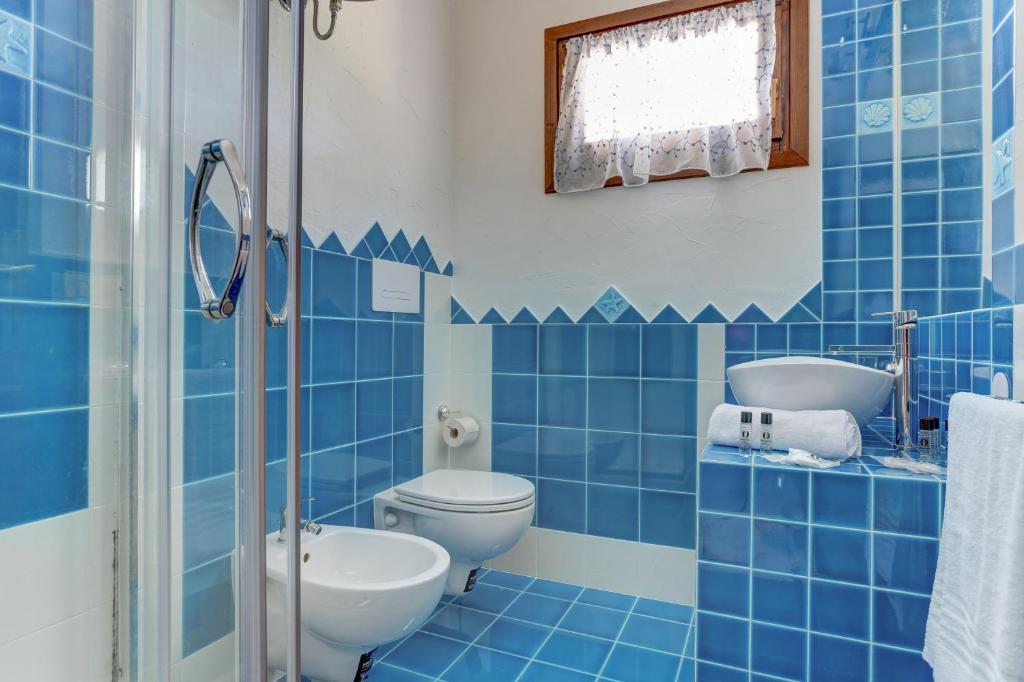a blue tiled bathroom with a toilet and a shower at VILLA MARIA - CAPO D'ORSO - HOME and MORE in Palau