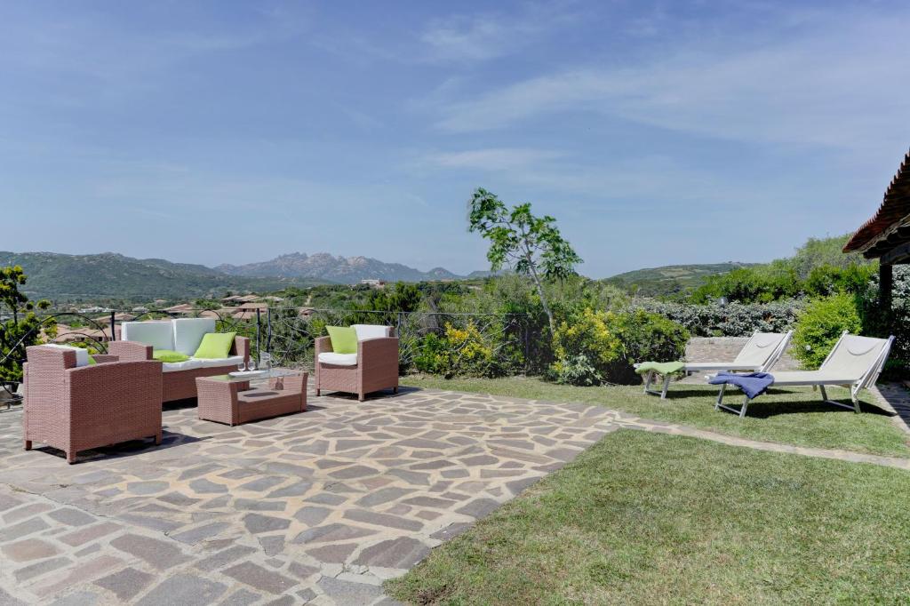 a patio with chairs and tables on the grass at VILLA MARIA - CAPO D'ORSO - HOME and MORE in Palau