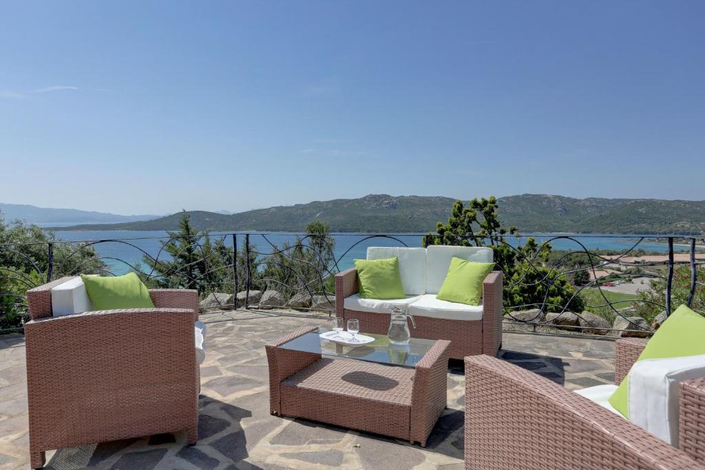 a patio with chairs and a table with a view of the water at VILLA MARIA - CAPO D'ORSO - HOME and MORE in Palau