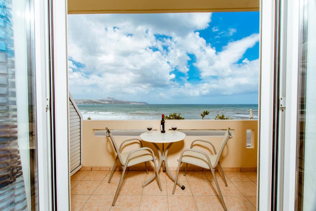 uma mesa e cadeiras numa varanda com vista para o oceano em Asterina Seaside Apartments em Kalyves
