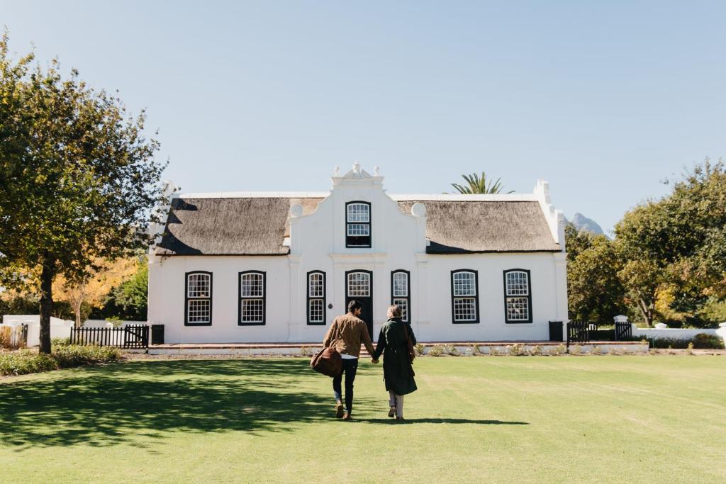 Due persone che camminano davanti a una casa bianca di Weltevreden Estate a Stellenbosch