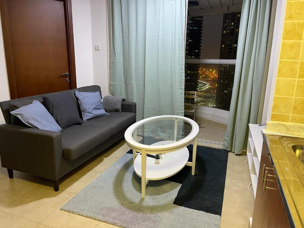 a living room with a couch and a table at Near Metro - Lovely Modern 1 Bedroom in JLT in Dubai
