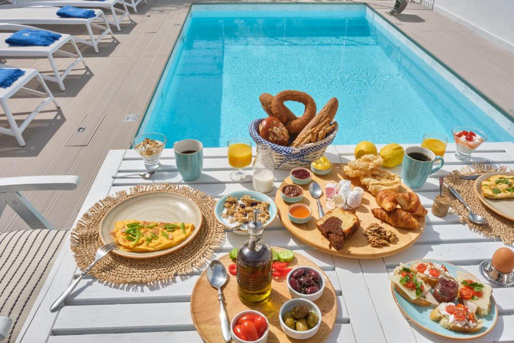 a table with food next to a swimming pool at Porto Vecchio Luxury Suites in Spetses
