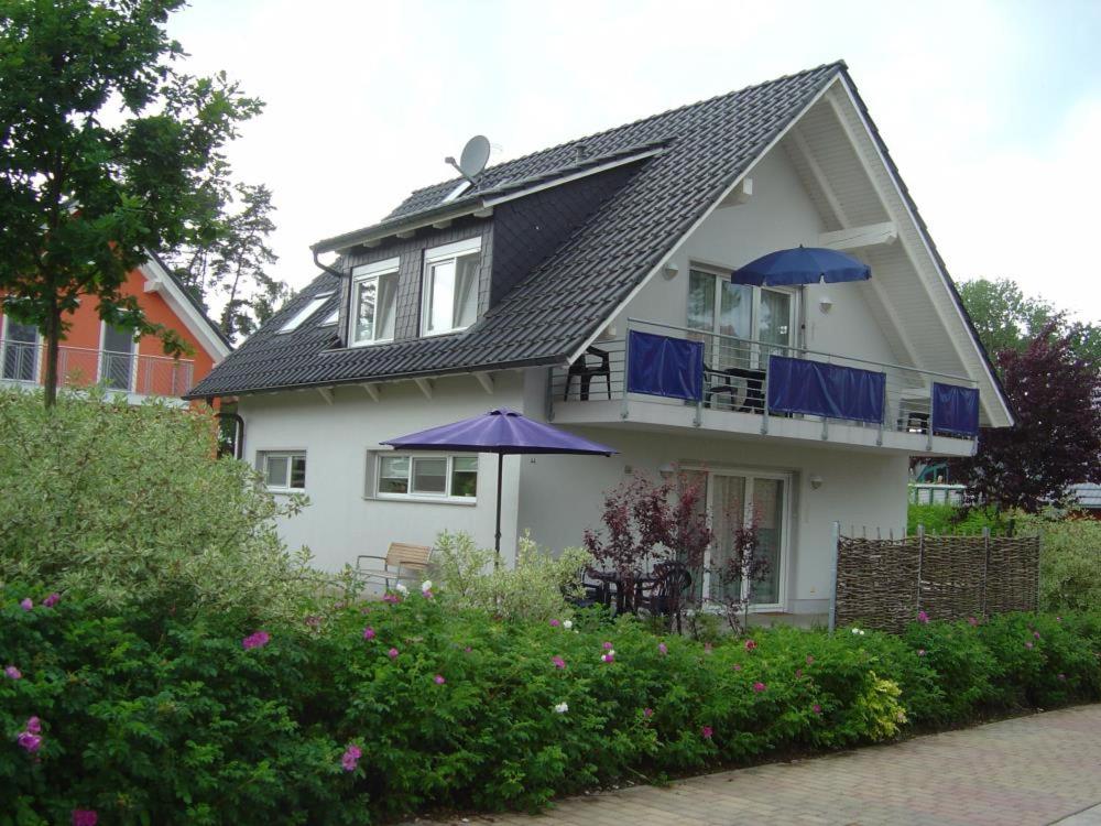 Casa blanca con sombrillas azules en el balcón en 44 EG - Ferienwohnung mit Terrasse und Seeblick, en Röbel