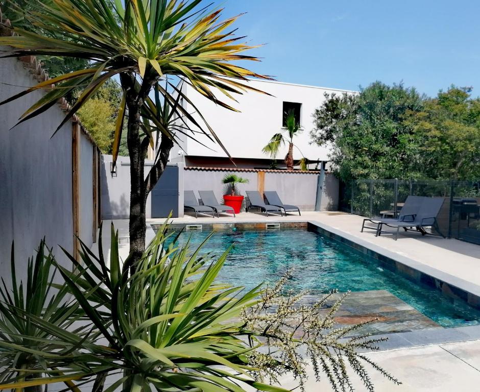 a swimming pool with chairs and a palm tree at Appartement Pérols Centre in Pérols