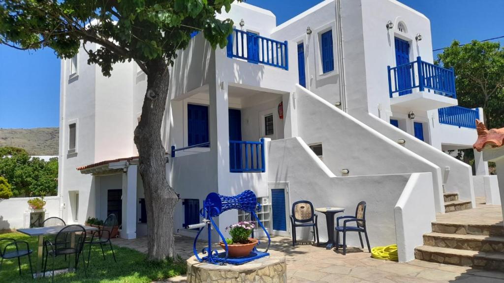 a white house with blue balconies and tables and chairs at RESTIA in Agios Petros