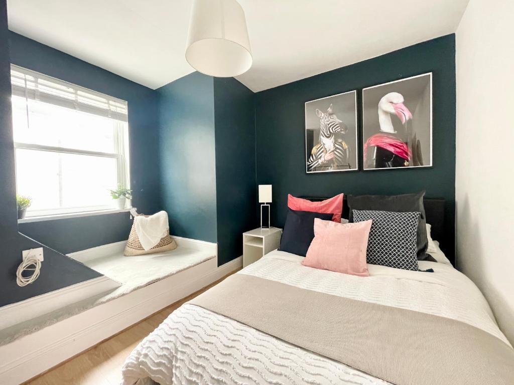 1 dormitorio con paredes azules y 1 cama con almohadas rosas en *NEW* Beautiful 2 Bedroom House in Central Location, en Londres