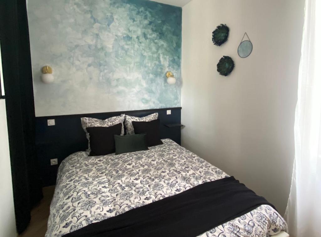 a bedroom with a bed and a painting on the wall at La Suite Dandy - Beau T2 -Terrasse, Parking gratuit, Climatisation in Bagnères-de-Bigorre