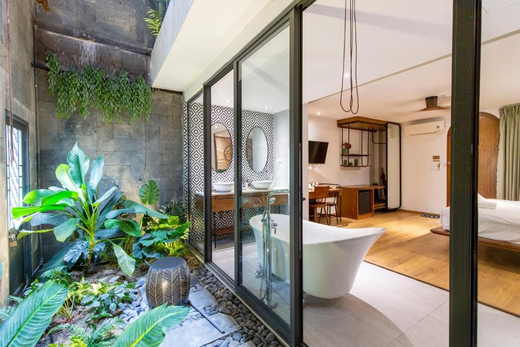 a bathroom with a bath tub and a bedroom at Seaforest Hotel by Haviland in Da Nang