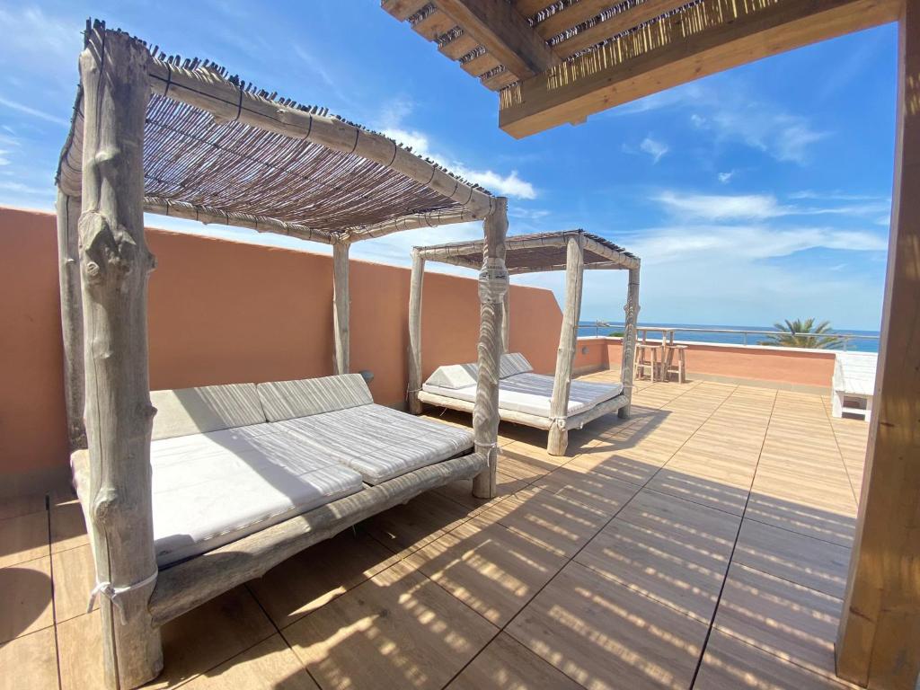 a bed on a deck with the ocean in the background at El Cortijo de Zahara by QHotels in Zahara de los Atunes
