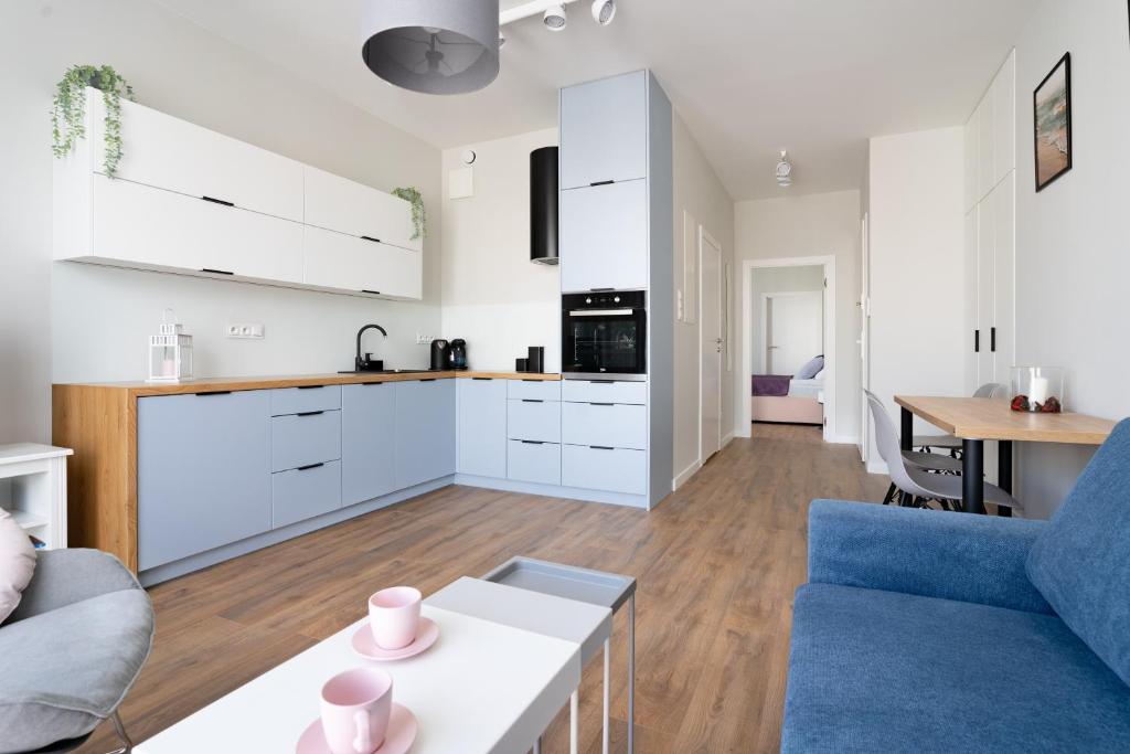 a kitchen and living room with white cabinets and a blue couch at INA Rent - Nadmorski Dwór in Gdańsk