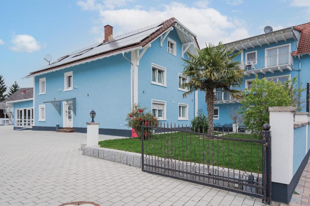 a blue house with a fence in front of it at Park Hotel & Gästehaus Rust in Rust