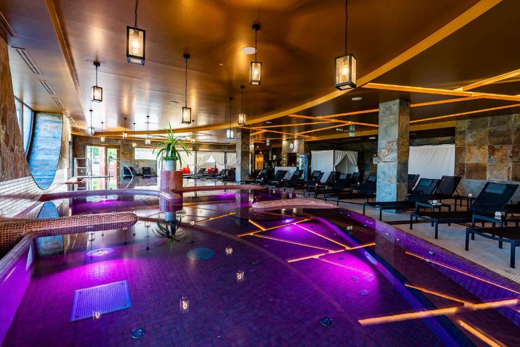 een zwembad met paarse lichten in een gebouw bij Allure Healthy Hotel & Spa in Eger