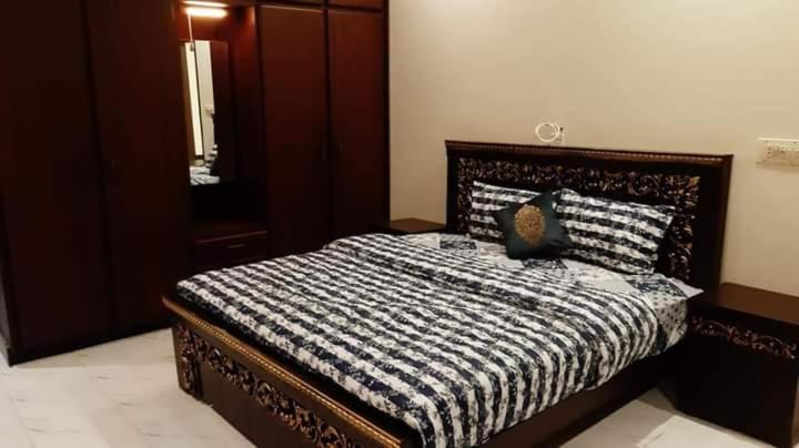 a bedroom with a bed with a black and white comforter at Hotel Royal Defence in Lahore