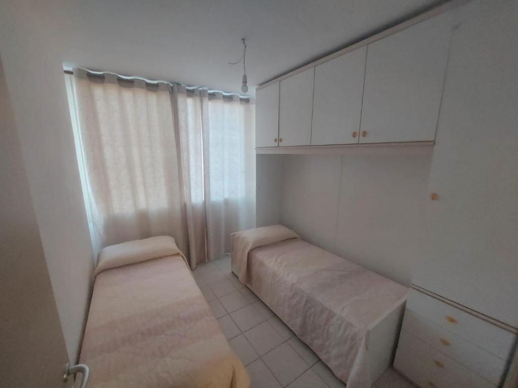 オルビアにあるFraSilviaの白い小さな客室で、ベッド1台と椅子が備わります。