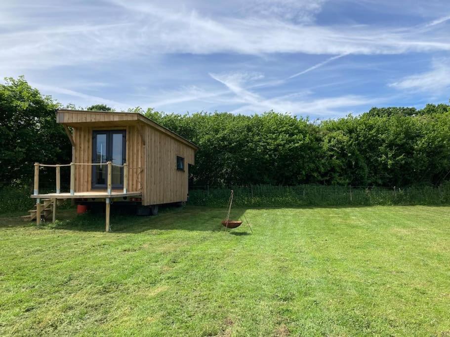 a small wooden cabin in a grassy field at Neddys Rest Luxury Horsebox Stay in Battle