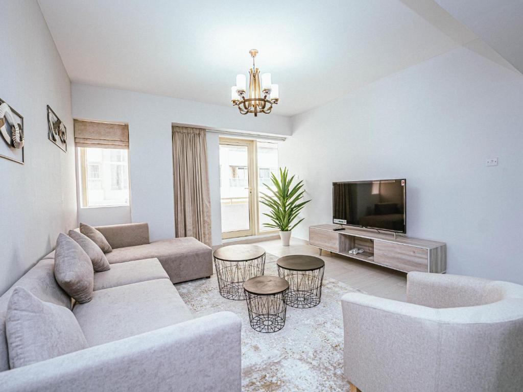 a living room with a couch and a tv at Beautifully Decorated & Homely 2 Bed apartment in Dubai
