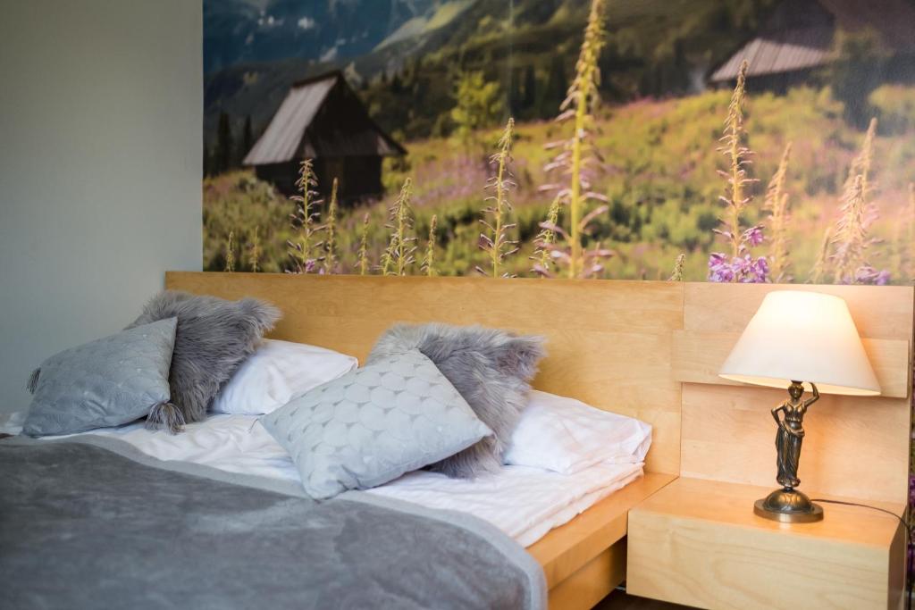 a bedroom with a bed with pillows and a painting at Pod Równią Centrum in Zakopane