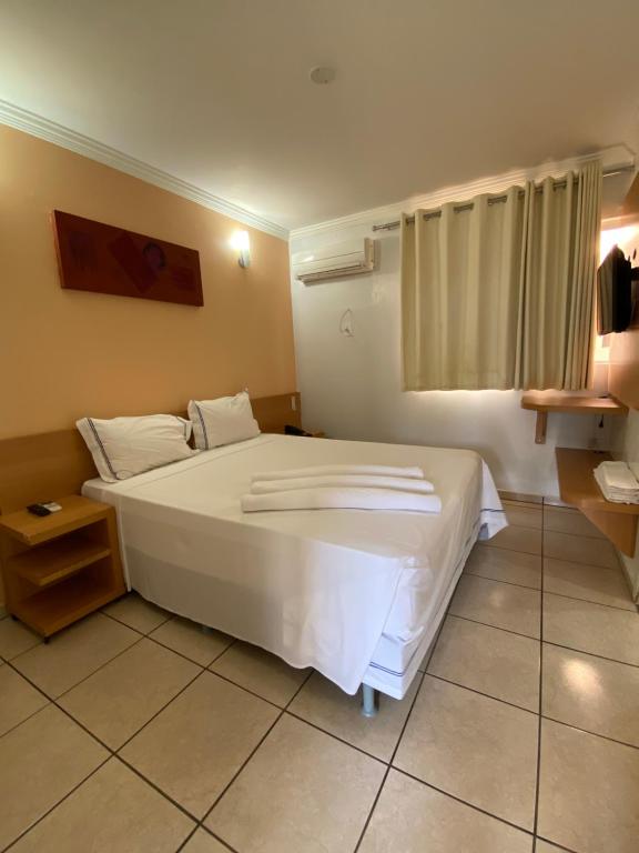 Un dormitorio con una cama blanca con toallas. en diRoma Internacional Resort com Piscinas 24h e um dia no Acqua Parque e Splash, en Caldas Novas