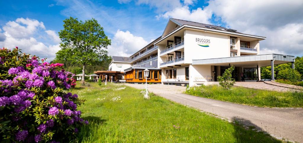 un bâtiment avec des fleurs violettes devant lui dans l'établissement BRUGGER' S Hotelpark Am Titisee, à Titisee-Neustadt