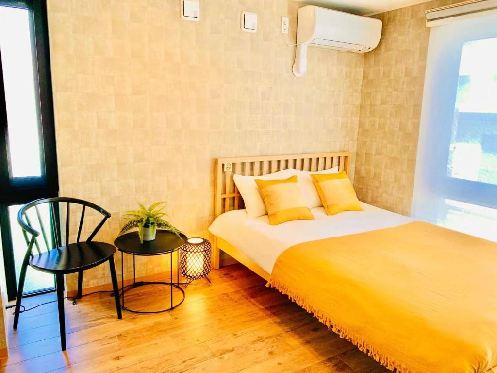 a bedroom with a bed with yellow pillows and a chair at TIME SHARING STAY Ikebukuro in Tokyo
