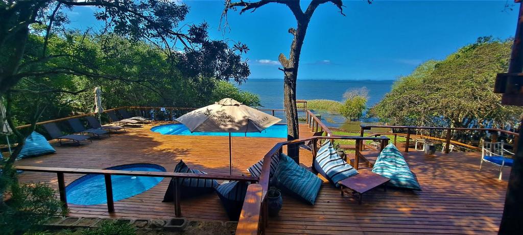 a wooden deck with blue pillows and an umbrella at Nibela Lake Lodge by Dream Resorts in Hluhluwe