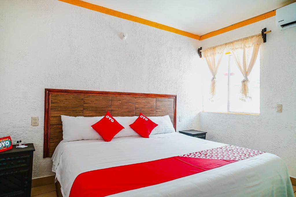 1 dormitorio con 1 cama grande con almohadas rojas en OYO Hospedaje Colibri en Chiapa de Corzo