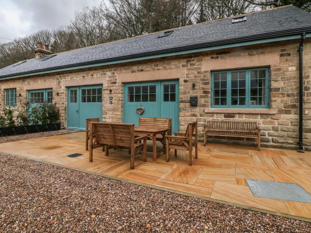 un patio con mesa y 2 bancos frente a un edificio en Chestnut Cottage en Sheffield