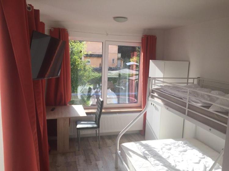 a bedroom with a bed and a desk and a window at Gästehaus in der Friedensfabrik in Wanfried