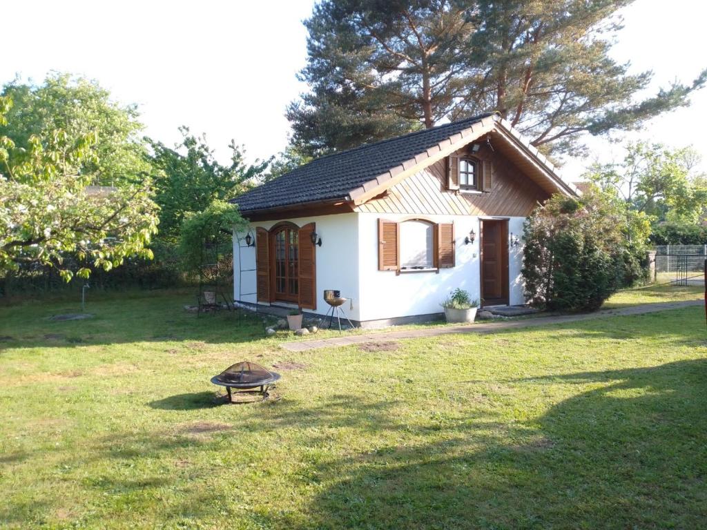 una pequeña casa blanca en un jardín en Ferienhaus Kranichhorst - Exklusiv-Nutzung mit großem Garten und Strandnähe en Bodstedt