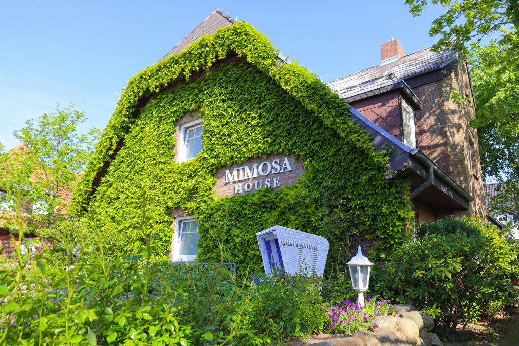 a house covered in ivy with a sign on it at Mimosa House in Westerland (Sylt)